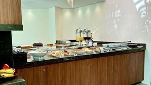 Una barra de desayuno moderna con mostrador de madera, una variedad de alimentos para el desayuno y una lámpara decorativa.