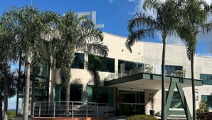 Un edificio moderno con techo plano, ventanas amplias y un espacio al aire libre cubierto con asientos.