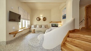 Un grand salon comprenant un canapé, un téléviseur, une cheminée et un escalier.