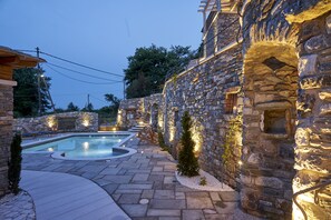 A stone-walled pool area with a stone pathway, benches, and a small tree. - Sunrise Pelion Villas Tsagkarada (Zagora-Mouresi)