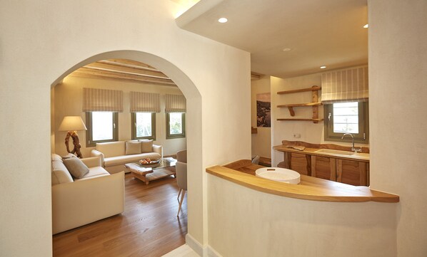 A spacious living area with a sofa, coffee table, and a kitchen area with a sink and wooden counter.