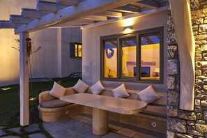 An outdoor seating area with a bench and a sofa, a stone wall, and a window with a view. - Sunrise Pelion Villas Tsagkarada (Zagora-Mouresi)