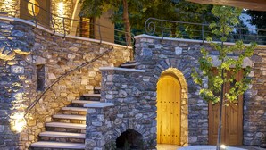 Un escalier en pierre mène à une porte en bois, qui est elle-même entourée d’un mur de pierre et d’un petit arbre.