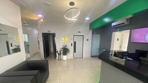 Un área de recepción moderna con mostrador, asientos y una pared decorada en verde.