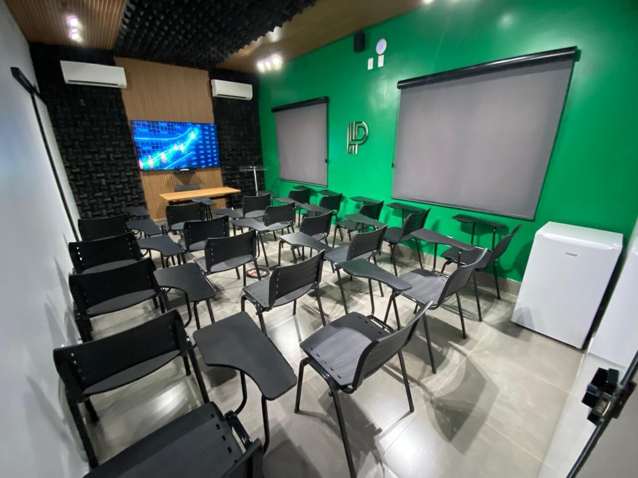 Ett konferensrum med rader av stolar, en stor skärm och en projektor.