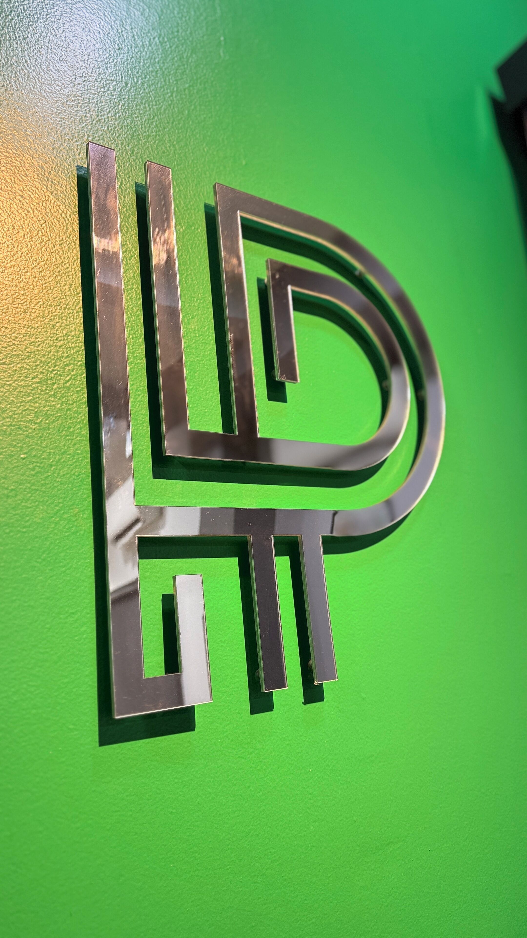 A metallic logo on a green background.