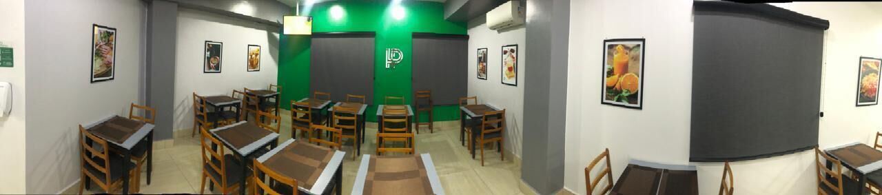 Une pièce aménagée avec des tables et des chaises pour les repas, un mur d’accent de couleur verte et des tableaux encadrés accrochés aux murs.