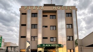 Un hotel de varios pisos con un letrero que dice 'Plaza Hotel' en la entrada.