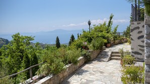 A stone pathway leading uphill with a view of the sea and mountains in the distance. - To Stefani tis Makrinas (Volos)