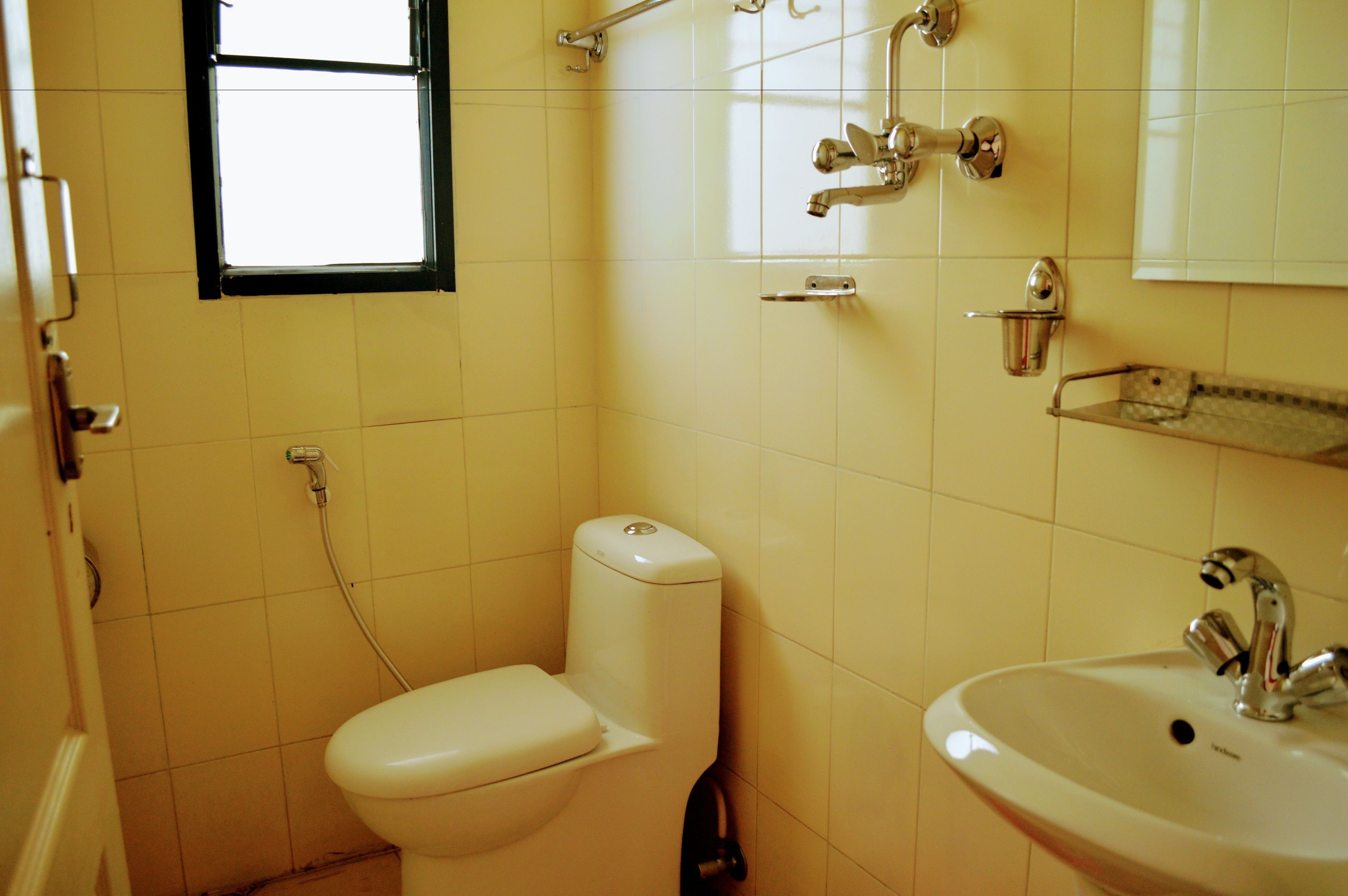 A small bathroom with a toilet, sink, and a window.