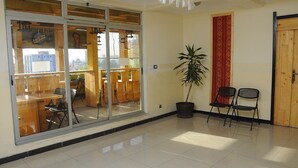 A spacious room with a large sliding glass door leading to an outdoor seating area. There is a potted plant and two chairs near the door. - Holly Wood Hotel (Addis Ababa)