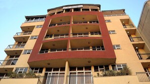 A multi-story hotel with a red and beige facade, balconies, and a sign indicating it is a hotel. - Holly Wood Hotel (Addis Ababa)