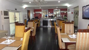 A restaurant with a bar area, dining tables with chairs, and a chandelier. - Adna Hotel (Lagos)