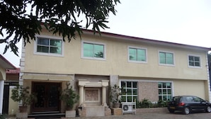 A two-story building with a beige facade, large windows, and a paved driveway. - Adna Hotel (Lagos)