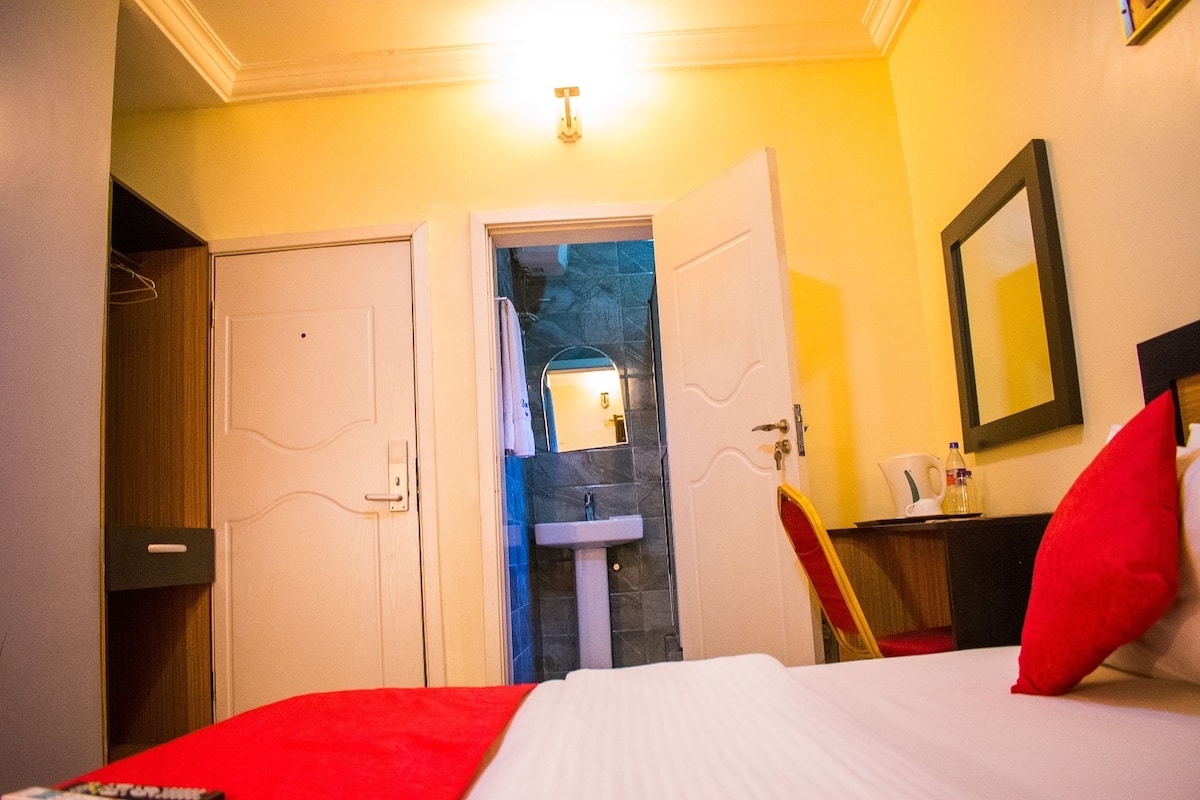 Una habitación de hotel con cama, baño con lavabo y un espejo en la pared.
