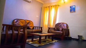 A living room with two leather sofas, a wooden coffee table, and a patterned rug. - Esporta Suites (Lagos)