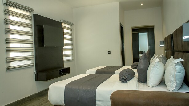 A modern hotel room with two beds, a flat-screen TV, and a large mirror. - Atlantic Hotel and Spa (Lagos)
