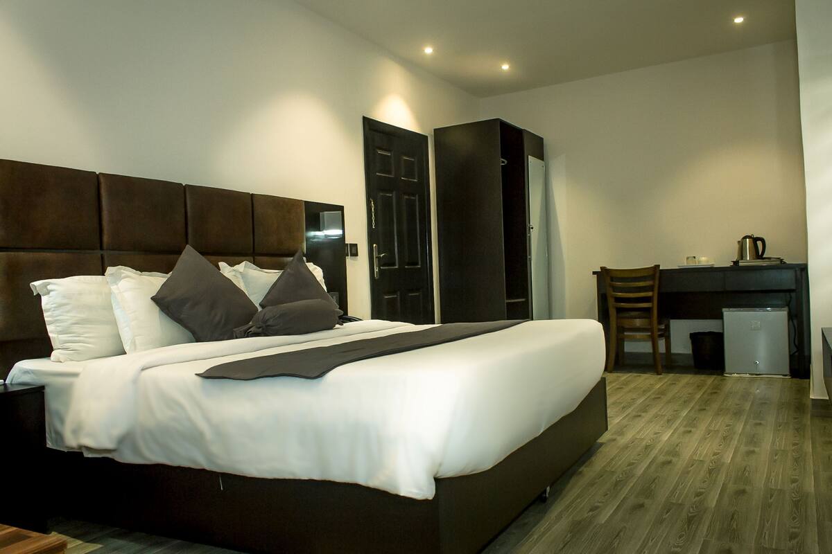 Una habitación de hotel moderna con una cama grande, un escritorio y una silla.