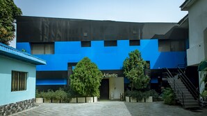 A modern building with a blue facade and the name 'Atlantic' visible. There are potted plants and a staircase leading to an upper level. - Atlantic Hotel and Spa (Lagos)