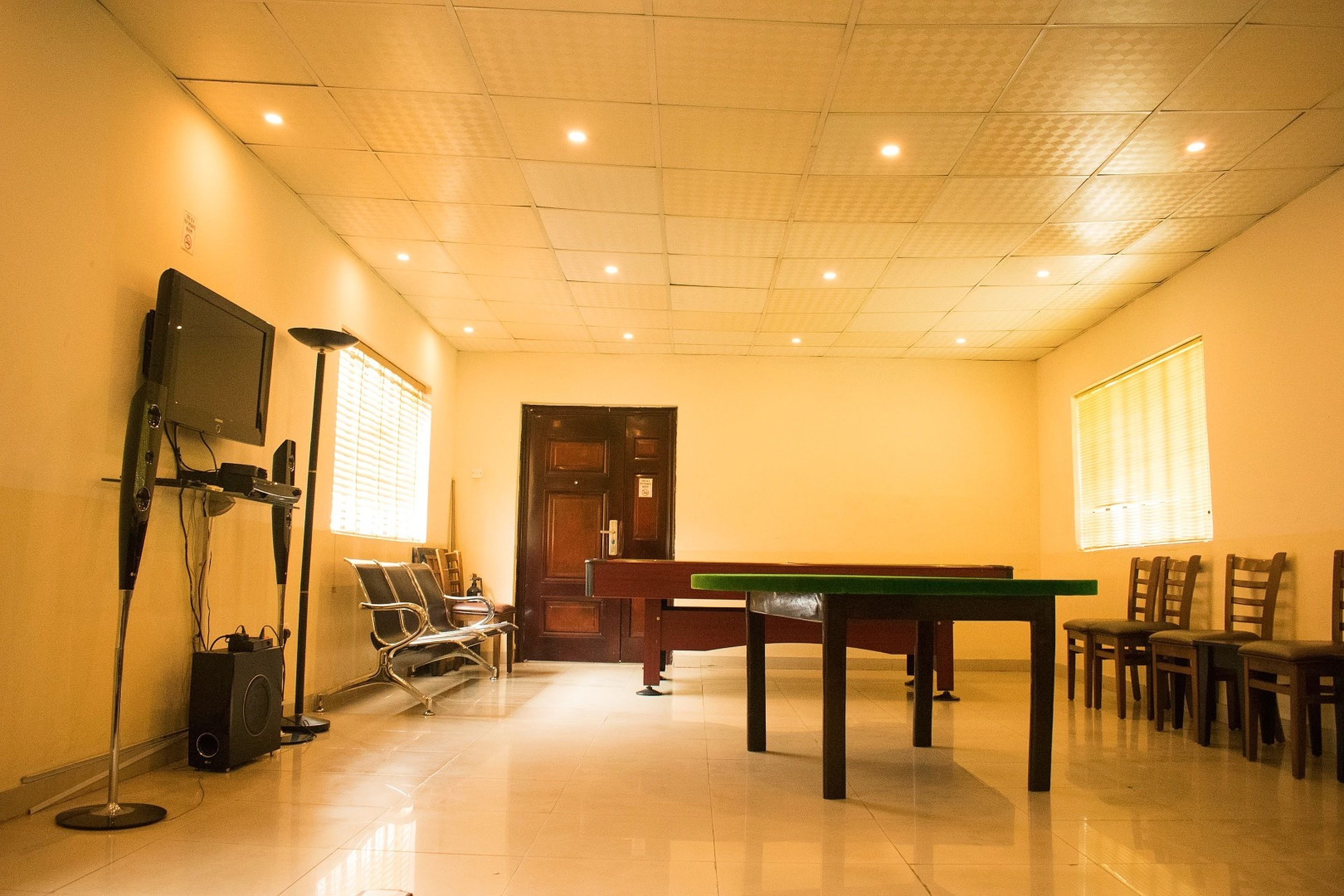 Una habitación con mesa de billar, sillas, televisión y altavoz.
