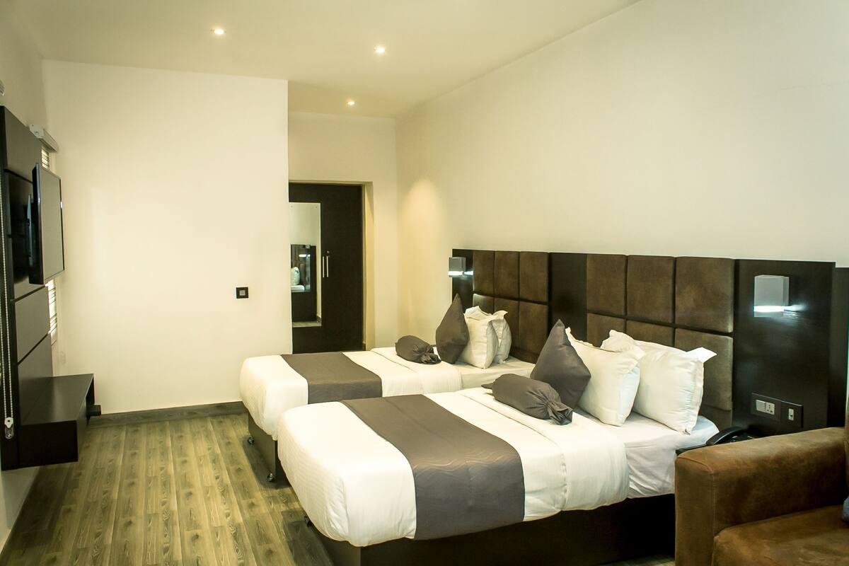 Habitación de hotel moderna con dos camas, un televisor de pantalla plana y suelo de madera.