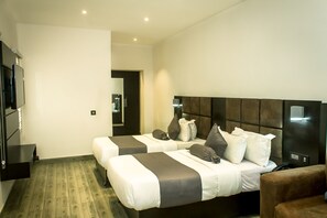 A modern hotel room with two beds, a flat-screen TV, and a wooden floor. - Atlantic Hotel and Spa (Lagos)