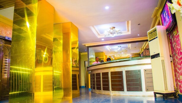 A hotel lobby with a reception desk, a chandelier, and a large mirror reflecting the interior. - Golden Destiny Hotel Limited (Lagos)