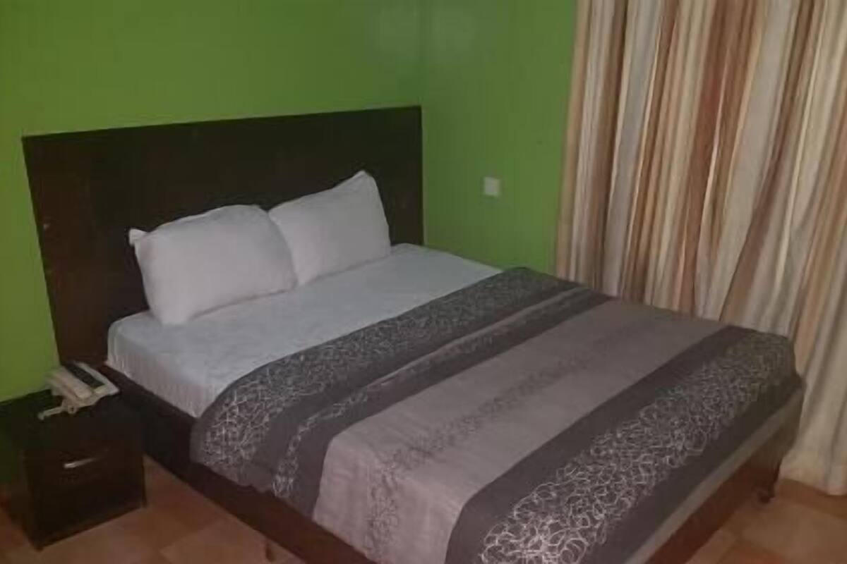 A bed with a headboard, a bedside table, and a curtain.