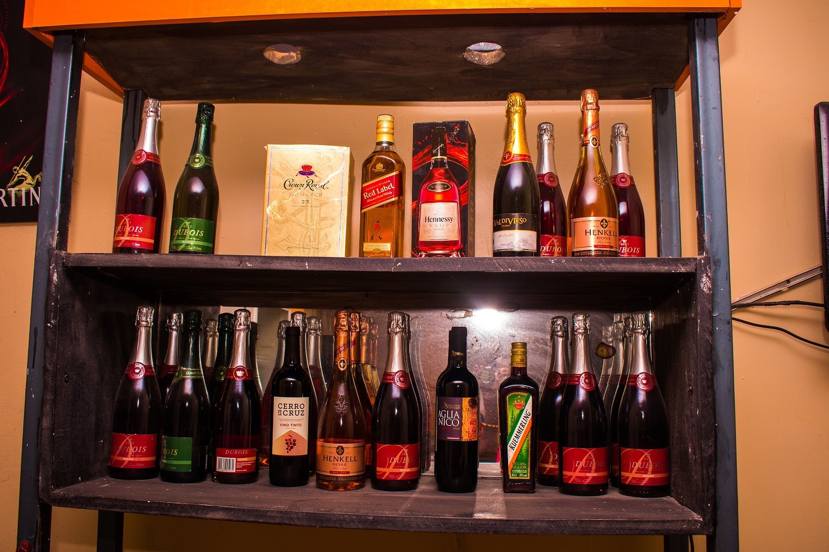 A shelf with various bottles of wine and liquor.