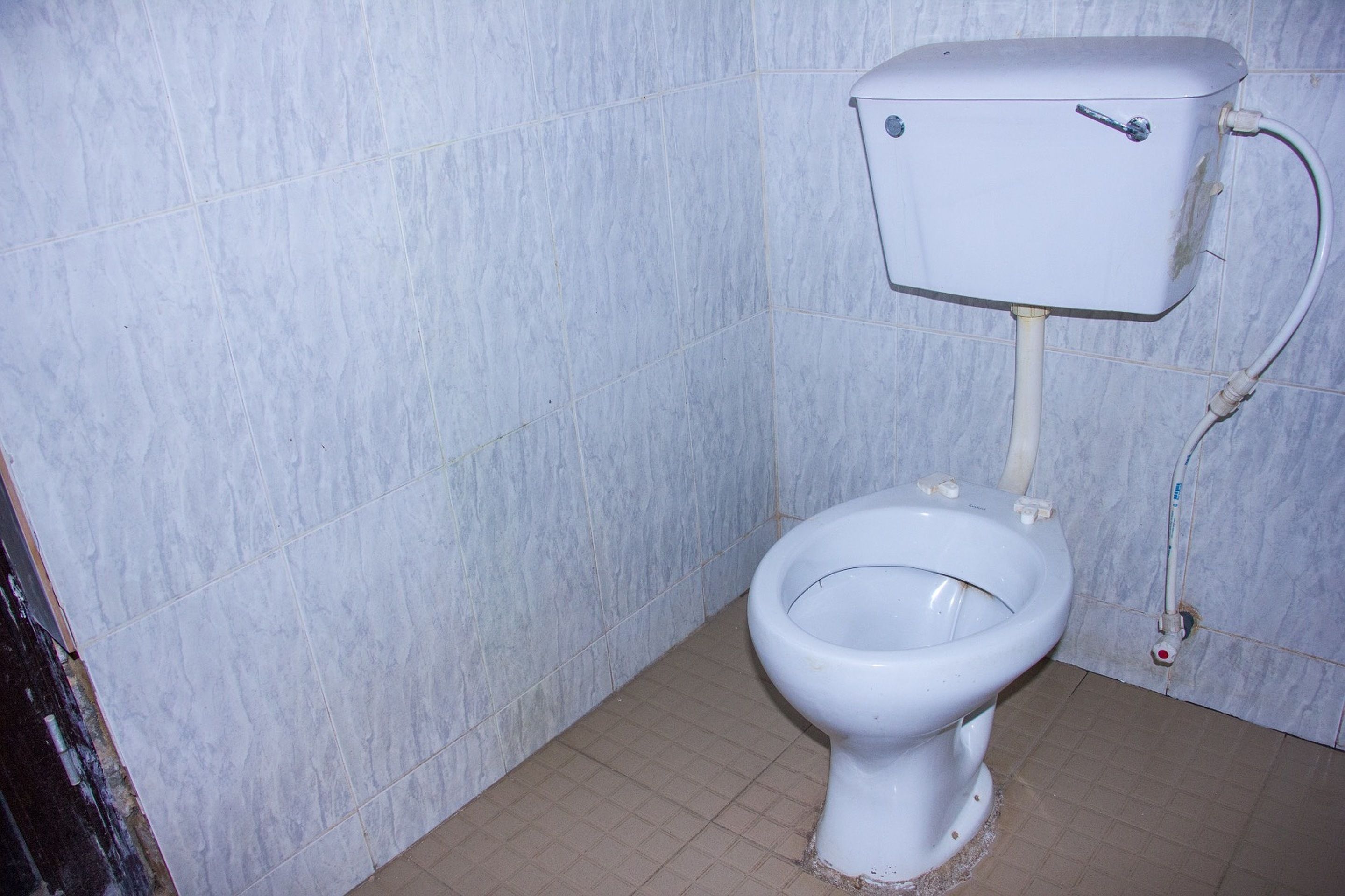 A standard toilet in a bathroom with tiled walls and floor.