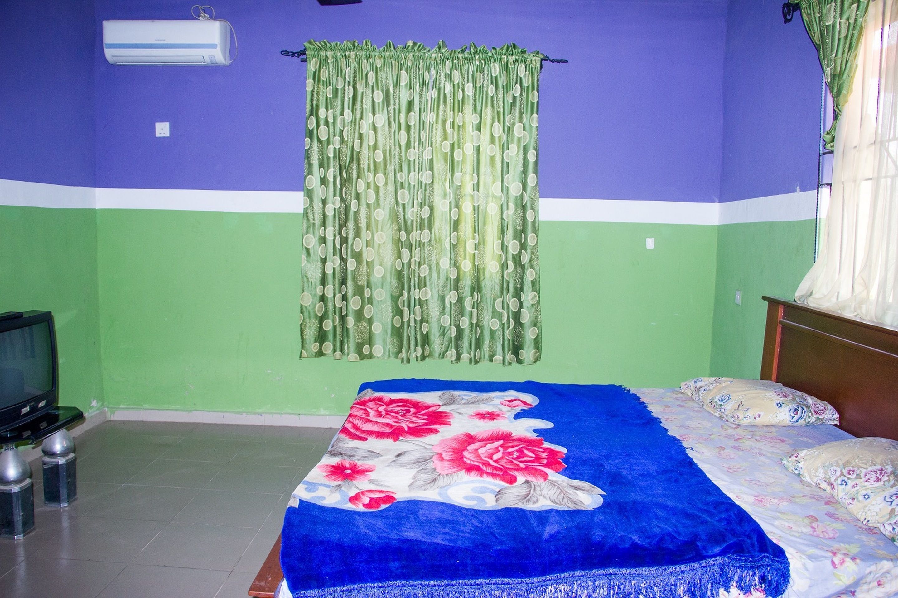 Una habitación con una cama, un televisor y una cortina.