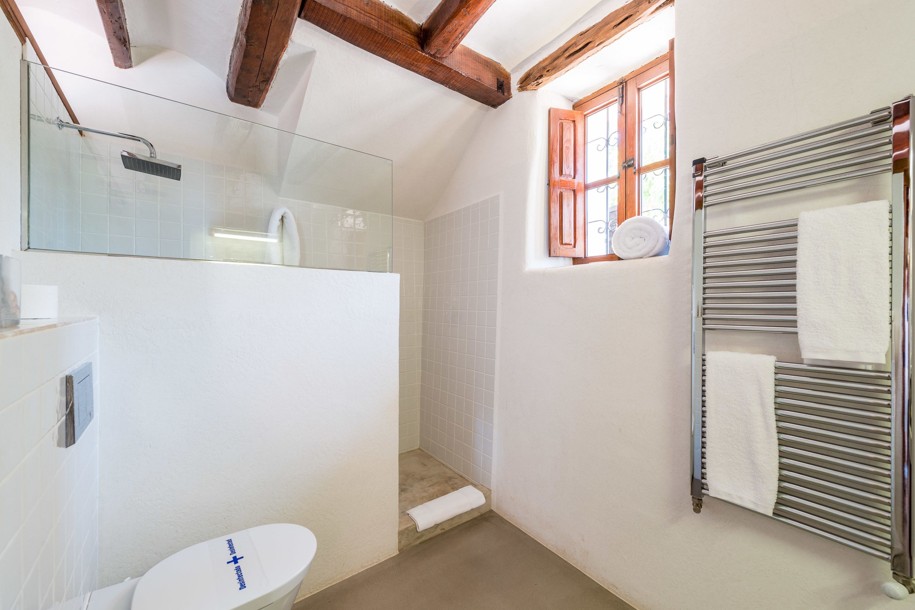 A bathroom with a toilet, shower, and towel rack.