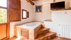 Un baño con bañera, escalones de madera, una ventana y un cuadro en la pared.