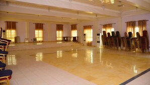 A spacious hall with a polished floor, rows of chairs, and large windows with curtains. - De' Nevilla Hotel (Kaduna)