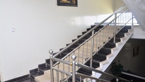 A staircase with black and white steps, metal railings, and a framed picture on the wall. - De' Nevilla Hotel (Kaduna)