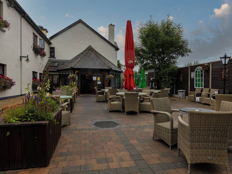 An outdoor patio area with wicker furniture and a red umbrella.