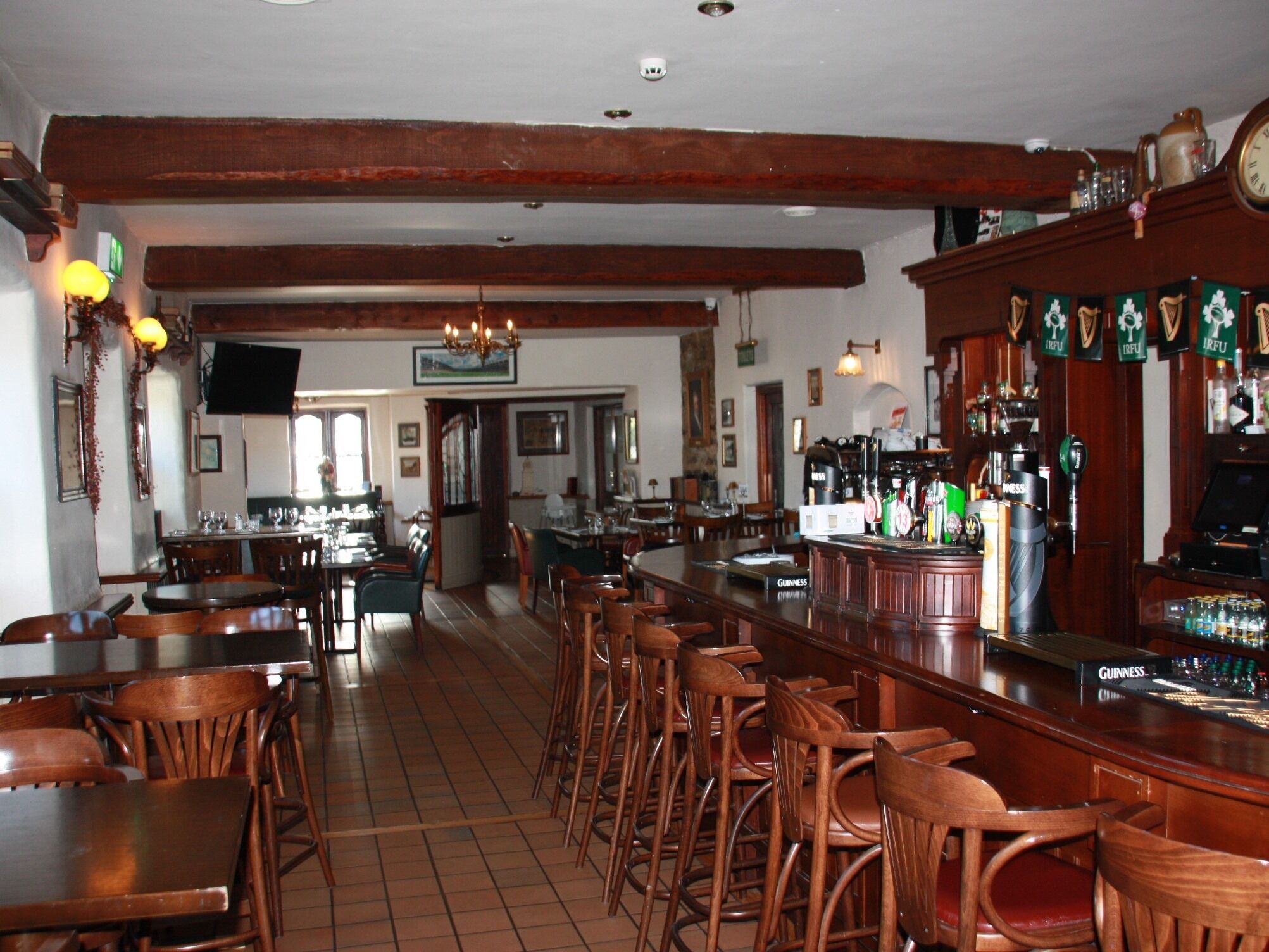Zona de bar con muebles de madera, una barra con grifo de Guinness y un televisor montado en la pared.