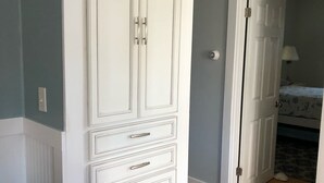 A room with a white wardrobe, a patterned rug, and a bed with a blue and white bedspread. - Renovated Cottage with nice yard and homey interior (Edgartown)