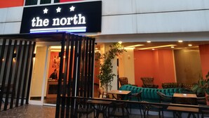 Un edificio con un letrero que dice "the north" y un área de estar con mesas y sillas afuera.