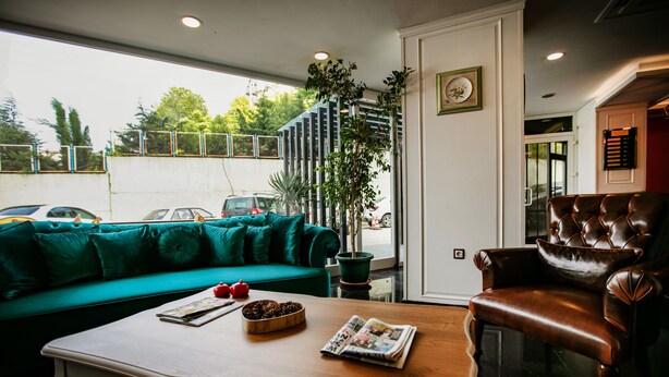 Una sala de estar moderna con un sofá azul turquesa, una mesa de centro de madera con revistas y una planta, y un sillón de cuero.