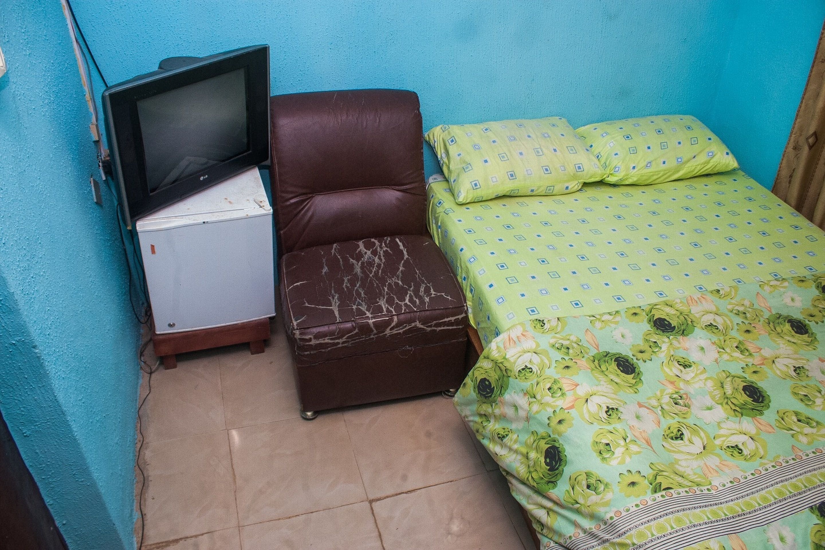 A small room with a bed, a chair, and a television.
