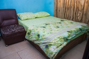 A room with a bed, a brown leather chair, and a small ottoman. - Janny Paul Hotel & Suites (Ijede)