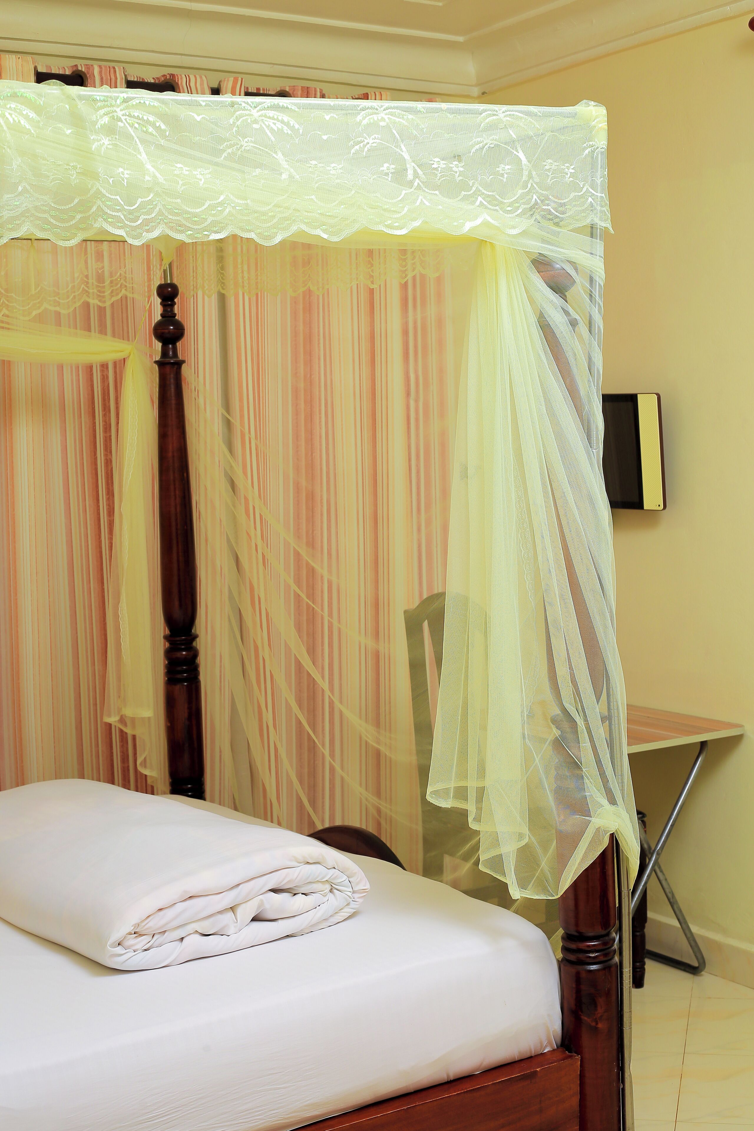 A neatly made bed with a white comforter and a wooden headboard.