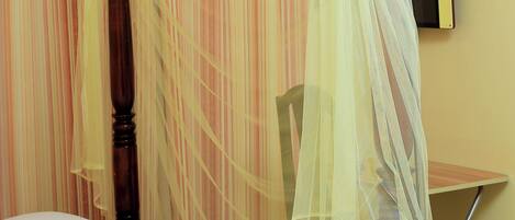 A neatly made bed with a white comforter and a wooden headboard.