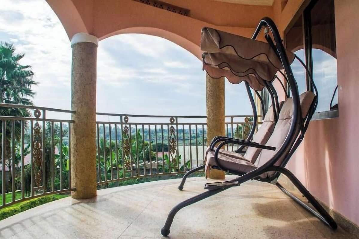 Un balcon avec une chaise, une vue sur la verdure et un ciel dégagé.