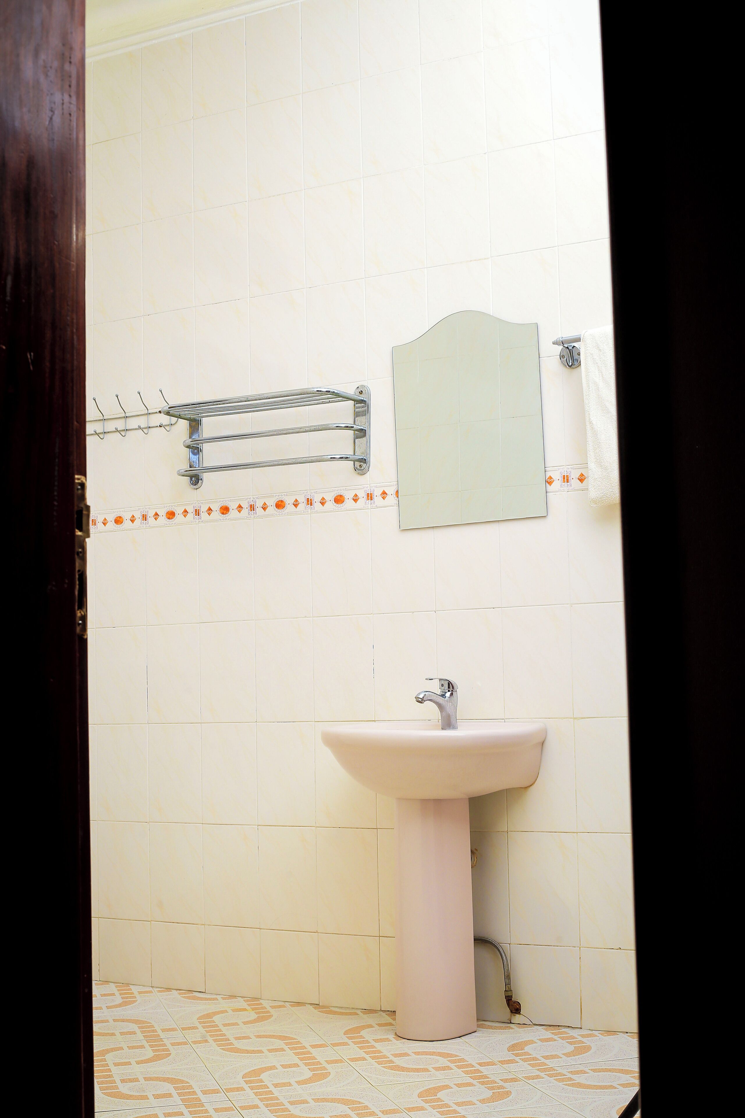A bathroom with a sink, mirror, towel rack, and patterned floor tiles.
