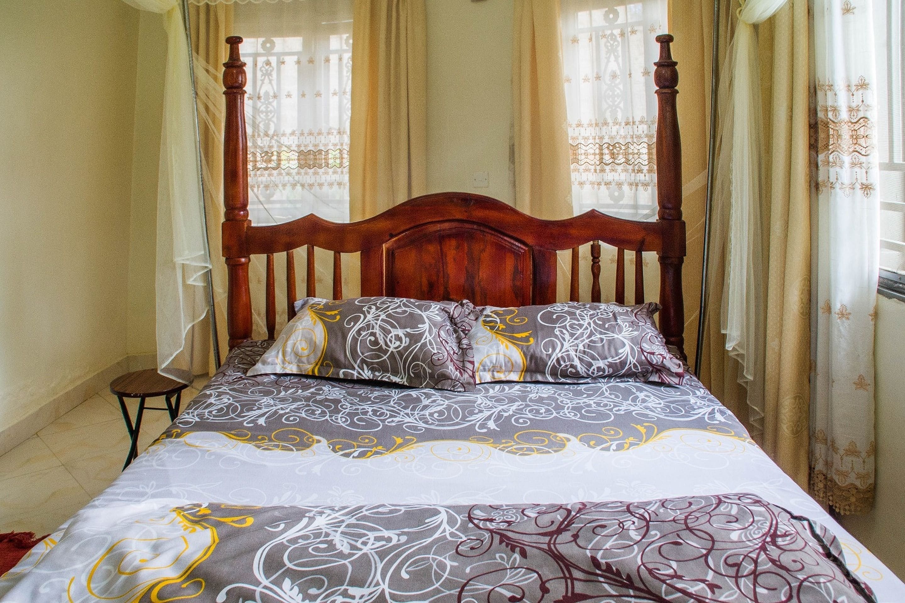 A bed with a wooden headboard, patterned bedding, and a small bedside table.