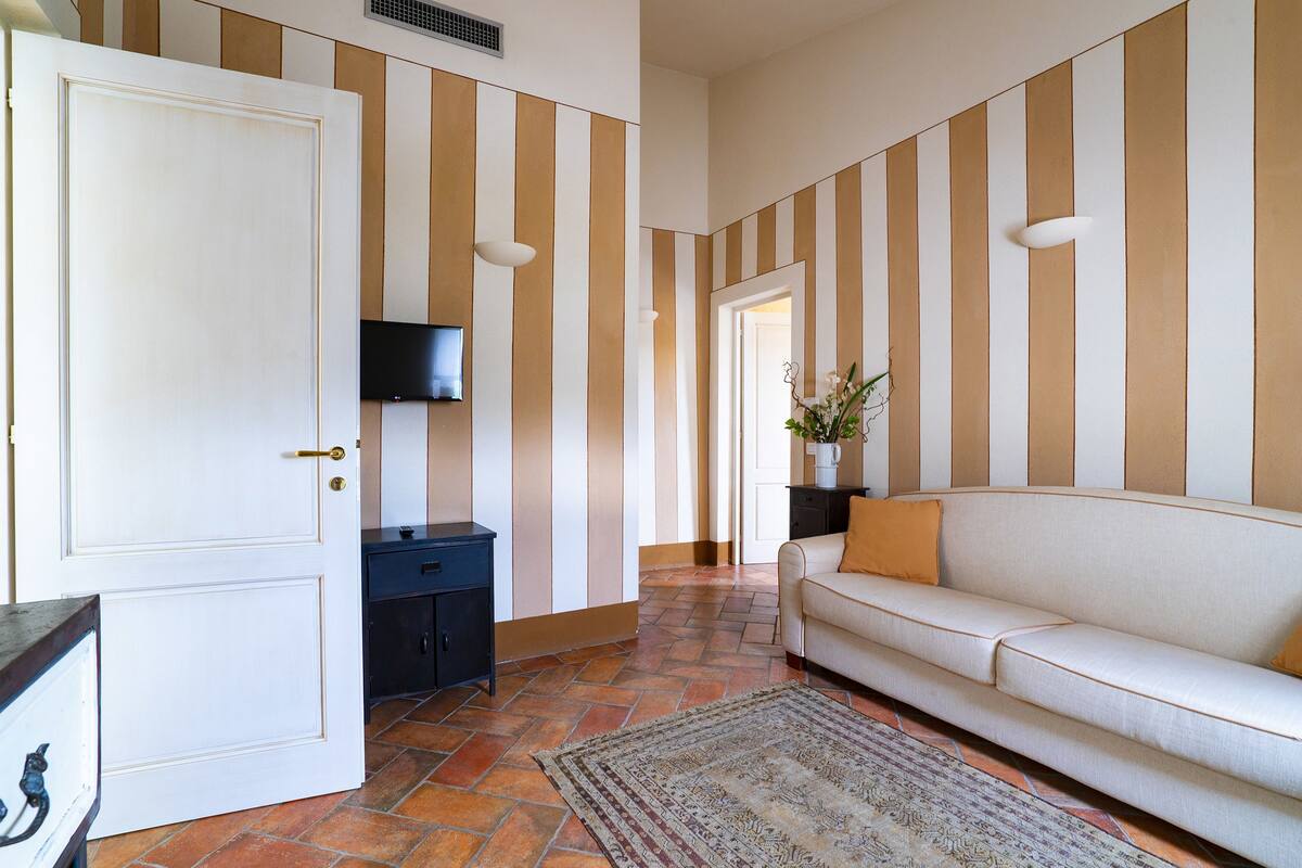 A hotel lobby with striped walls, a sofa, a television, and a door.