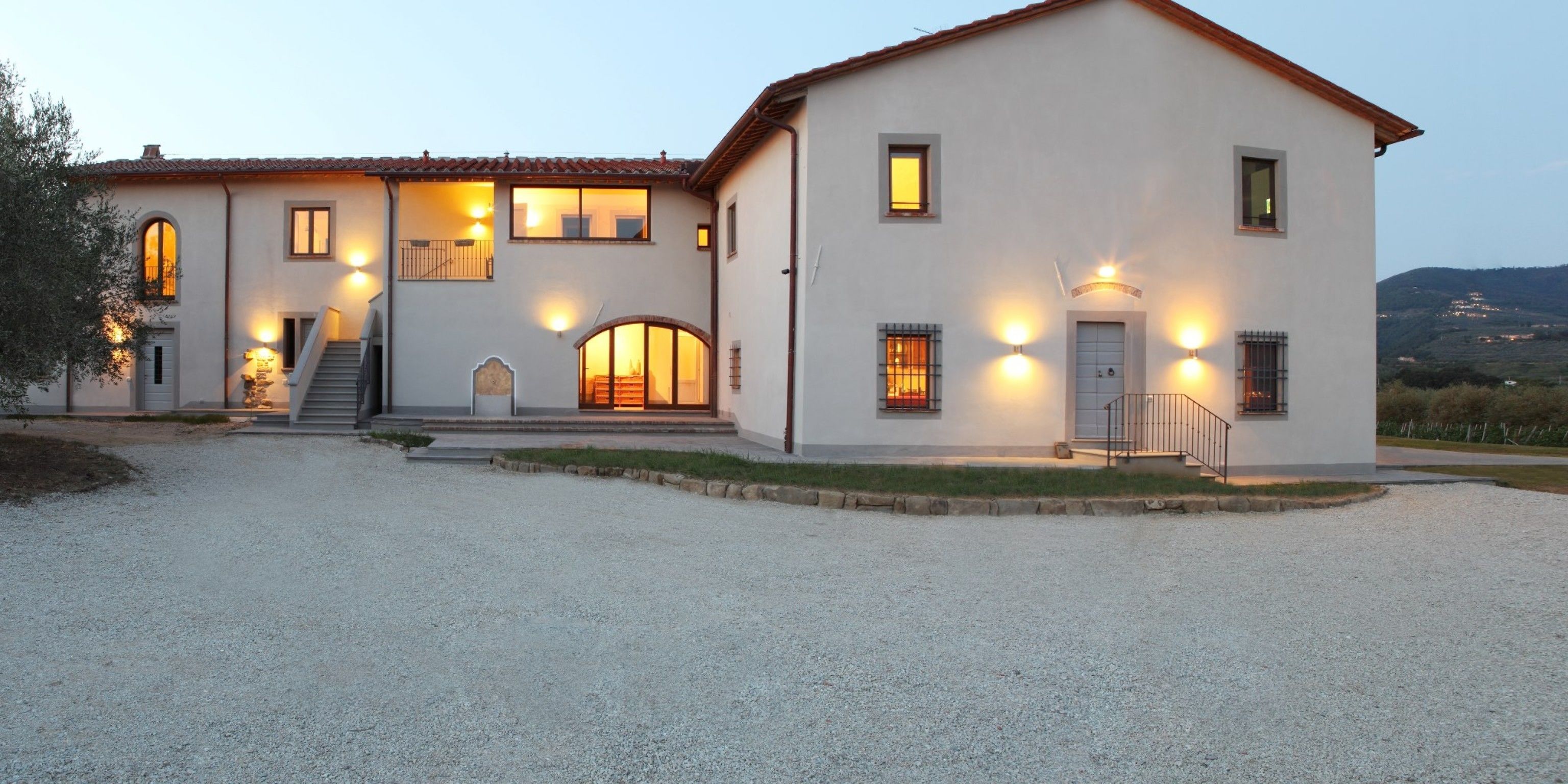 A two-story house with a gravel driveway, a staircase, and a view of the countryside.