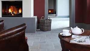 A cozy room with a fireplace, a wicker basket, and a table with a teapot and cups. - Agriturismo Cantagrillo (Vinci)
